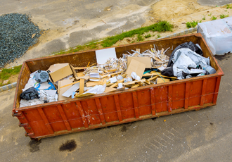 Kontenery na odpady budowlane, posegregowane na frakcje: cegły, gruz i drewno, zgodnie z nowymi przepisami segregacji.