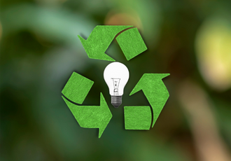 Zielony symbol recyklingu otaczający żarówkę, symbolizujący recykling i ponowne wykorzystanie zużytego sprzętu elektrycznego i elektronicznego.