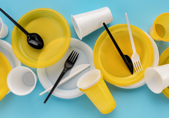 Zestaw jednorazowych plastikowych naczyń i sztućców (talerze, kubki, widelce, łyżki), symbolizujący produkty objęte