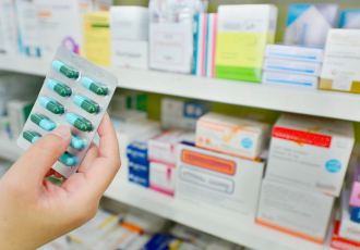 Dłoń trzymająca blister tabletek w aptece, symbolizująca obowiązki związane z odpadami medycznymi i farmaceutycznymi w systemie BDO.