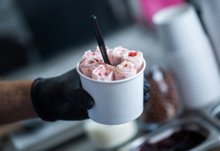 Sprzedawca podający lody w jednorazowym pucharku objętym przepisami SUP.